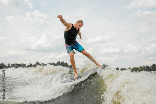 Athletic man wakesurfing on the board against the sky © fesenko