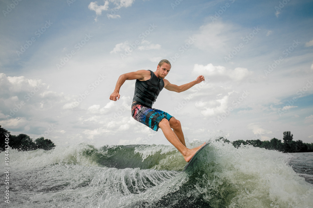 Handsome wakesurf rider jumping on the waves of a river Handsome wakesurf rider jumping on the waves of a river
