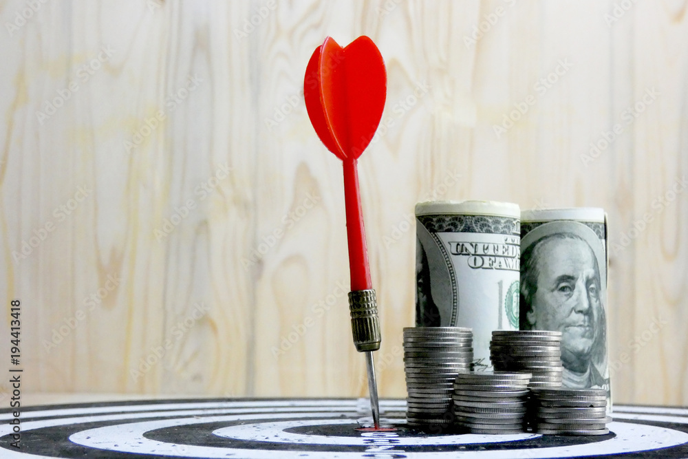 Red dart arrow hit the center target of dartboard and money coin metaphor marketing or saving money concept Red dart arrow hit the center target of dartboard and money coin metaphor marketing or saving money concept