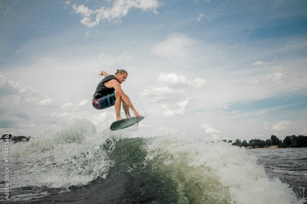 Young wakesurf rider jumping on the waves of the river