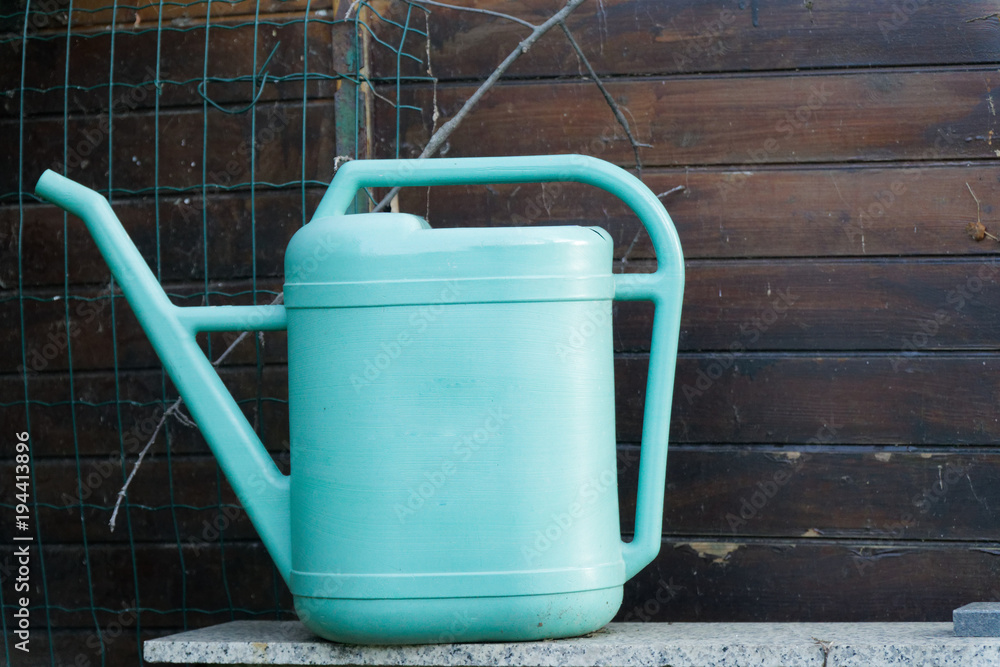 Old blue plastic watering can on wooden background Old blue plastic watering can on wooden background