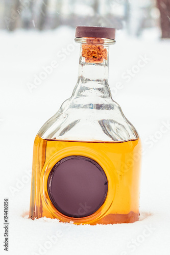 Glass bottle with elite alcohol and wax seal in the snow.