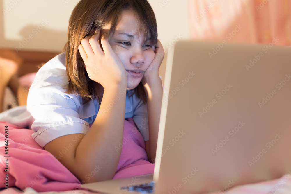 Fototapeta premium Asian young woman using laptop on her bed before sleep in selective focus..