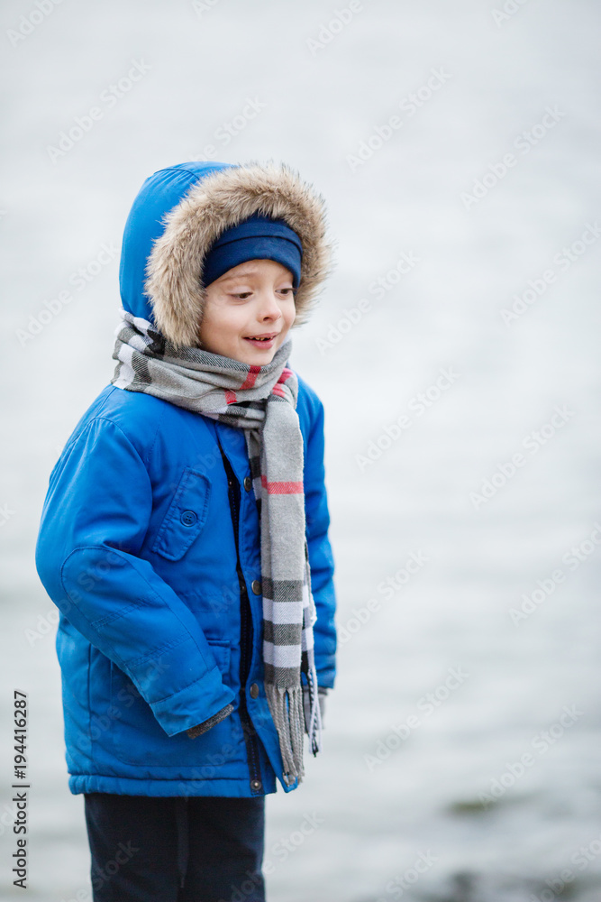 Little boy freezing. Cute little kid boy enjoying climbing on autumn day. Preschool child in blue autumnal clothes, having fun in garden or park on cloudy day. Little boy freezing. Cute little kid boy enjoying climbing on autumn day. Preschool child in blue autumnal clothes, having fun in garden or park on cloudy day.