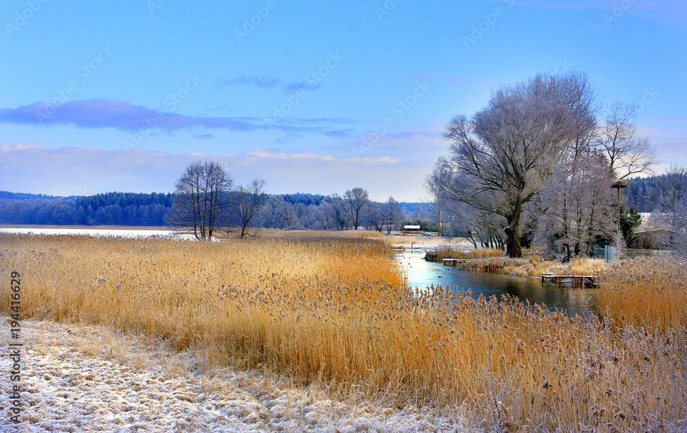 Winter landscape of woods and river covered with ice and snow in Masuria lakes district in Poland - Elk river estuary to Haleckie lake