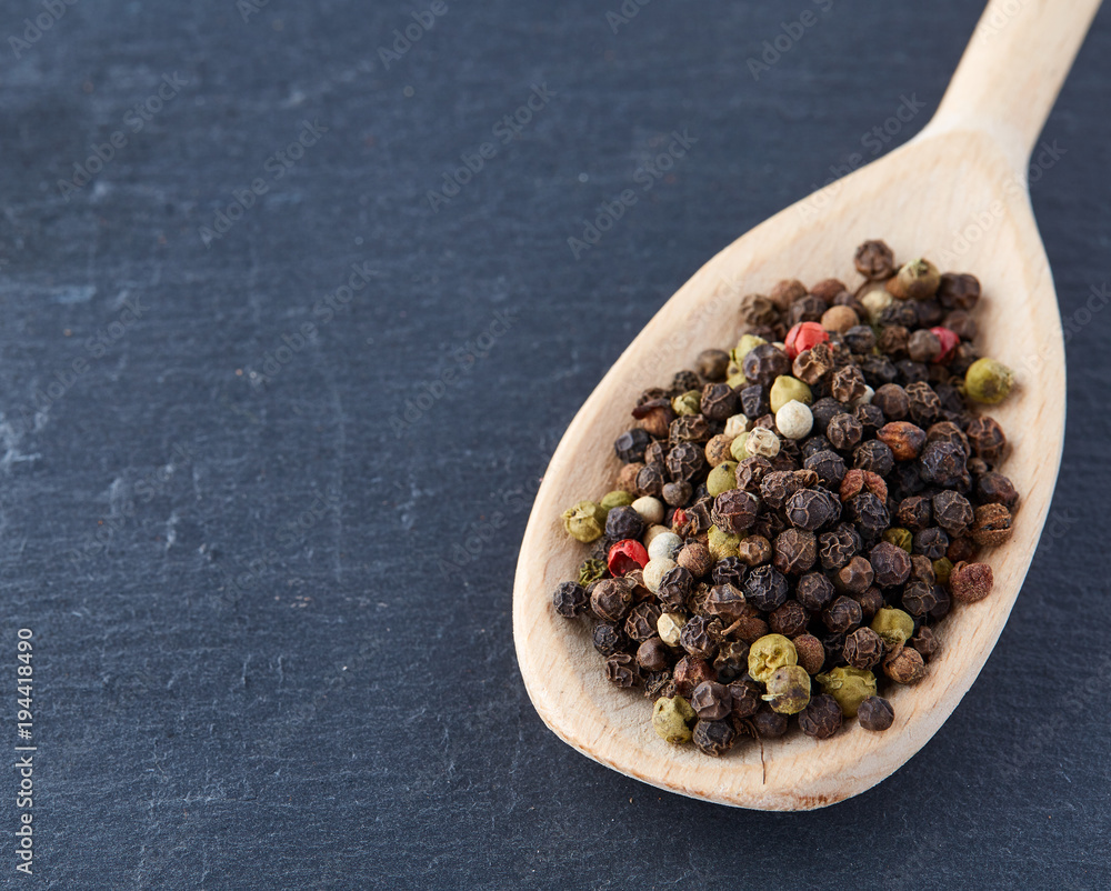 Top view of a wooden spoon full of allspice seeds isolated on dark background, shallow depth of field, front focus Top view of a wooden spoon full of allspice seeds isolated on dark background, shallow depth of field, front focus