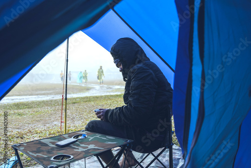 Asian man travel relax in the holiday. camping on the Mountain. sit relax on the chair. In the atmosphere rain fall have fog down. Thailand