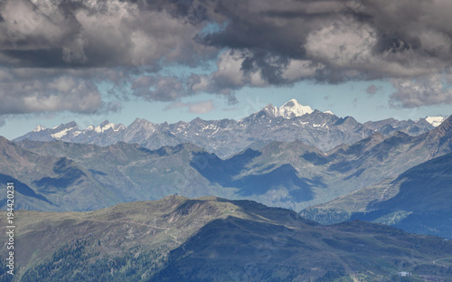 Gray clouds over snowcapped Rotspitze Pizzo Rosso peak and sunlit gray rocky ridges of Venediger Group and Villgraten Mountains Defereggen Alps Hohe Tauern East Tyrol Austria Europe © nogreenabove2k