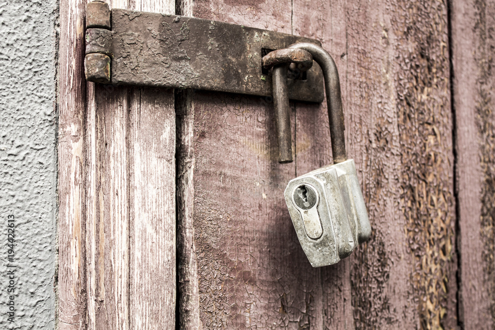 Old padlock on a background of a wooden door Old padlock on a background of a wooden door