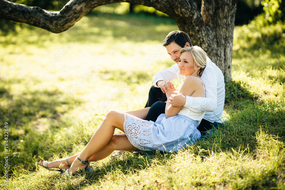 evening walk of a couple in love. A guy and a girl are sitting on the grass at sunset evening walk of a couple in love. A guy and a girl are sitting on the grass at sunset