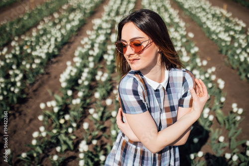 Young happy Woman in sunglasses in field of white tulips