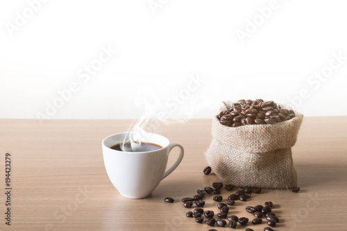 Coffee cup with coffee beans placed on a wooden table.