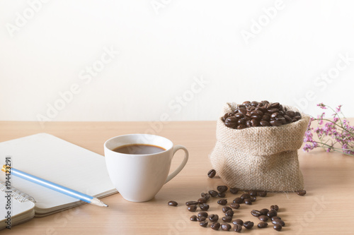 Coffee cup with coffee beans placed on a wooden table.