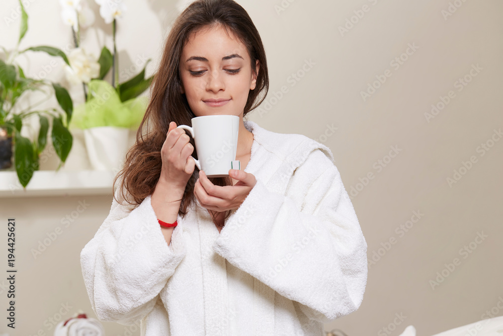 young woman relaxing and drinking a cup of tea at spa salon young woman relaxing and drinking a cup of tea at spa salon