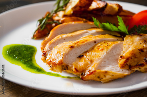 Grilled chicken breast with potato in a plate on wooden table