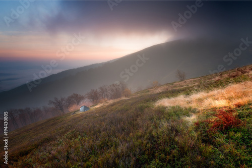 Tourist tent in camp among meadow in the mountain at sunrise