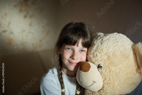 little girl hugging teddy bear indoor in her room, devotion concept, big bear toy