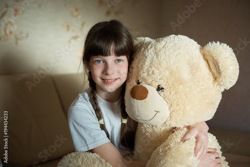 little girl hugging teddy bear indoor in her room, devotion concept, big bear toy