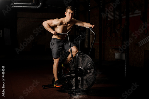 Young and handsome man practicing crossfit using an exercise equipment in a gym