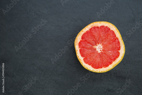 Pink grapefruit on dark background with copy space