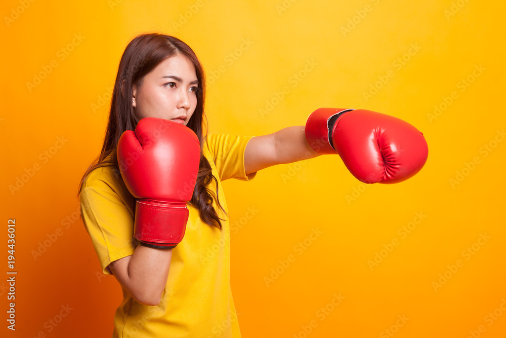 Young Asian woman with red boxing gloves in yellow dress Young Asian woman with red boxing gloves in yellow dress