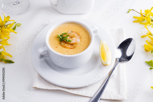 Creamy tomato soup with seafood and lemon on a white background.