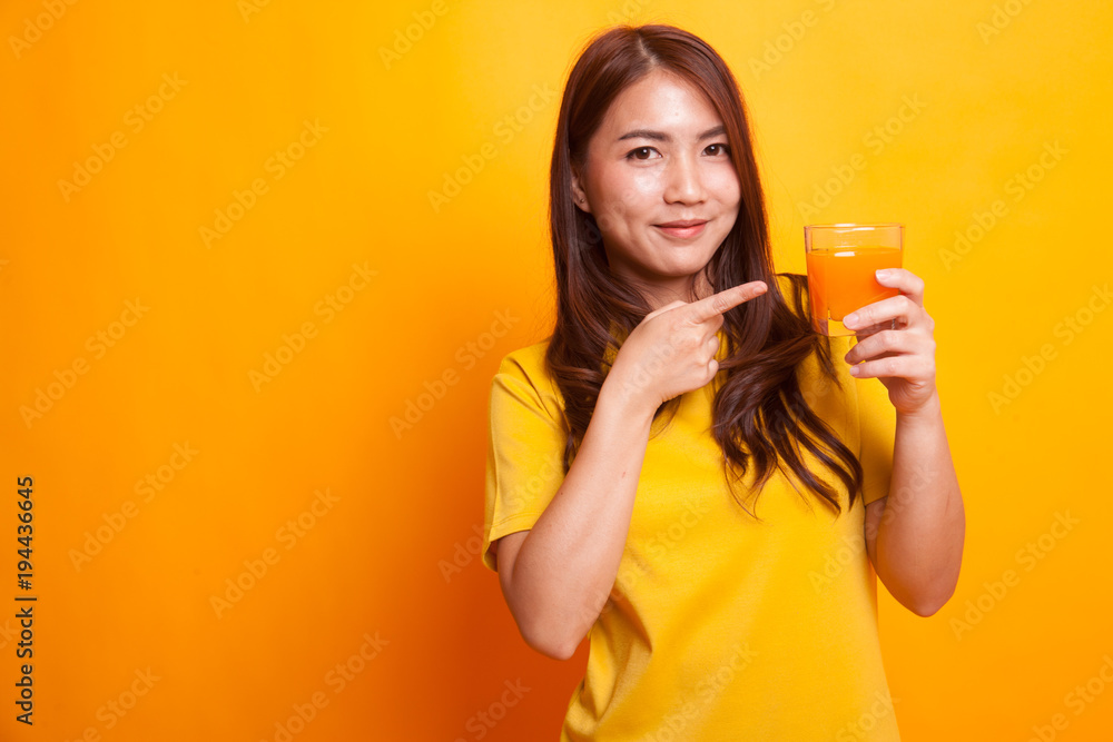 Young Asian woman point to orange juice in yellow dress Young Asian woman point to orange juice in yellow dress