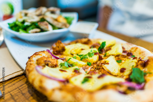Macro closeup of small individual pineapple pizza on plate in restaurant