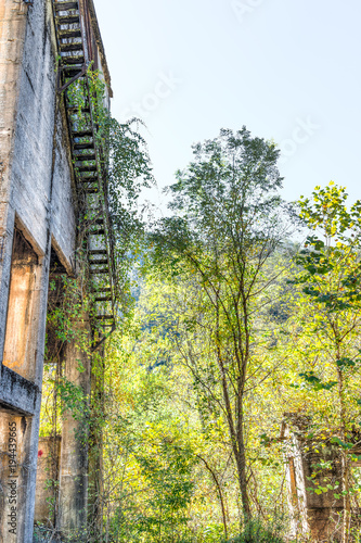 Abandoned retro vintage concrete building exterior in Thurmond, West Virginia ghost town with decaying structure walls, windows, fire escape and green trees photo