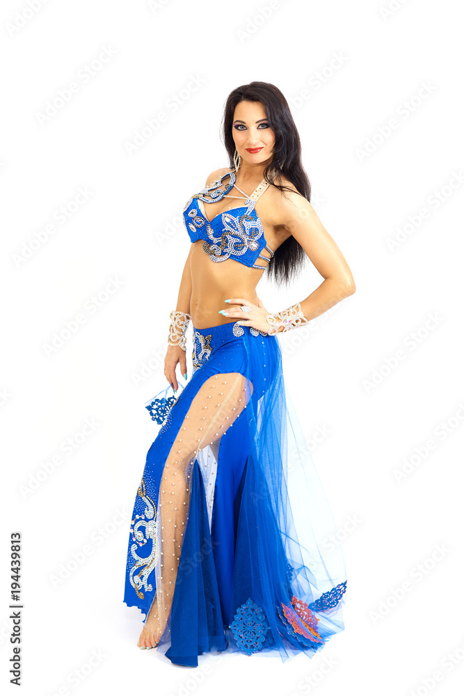 A young dancer in blue clothes performs an oriental belly dance. Isolate. Beautiful girl in bright national clothes dancing on white background.