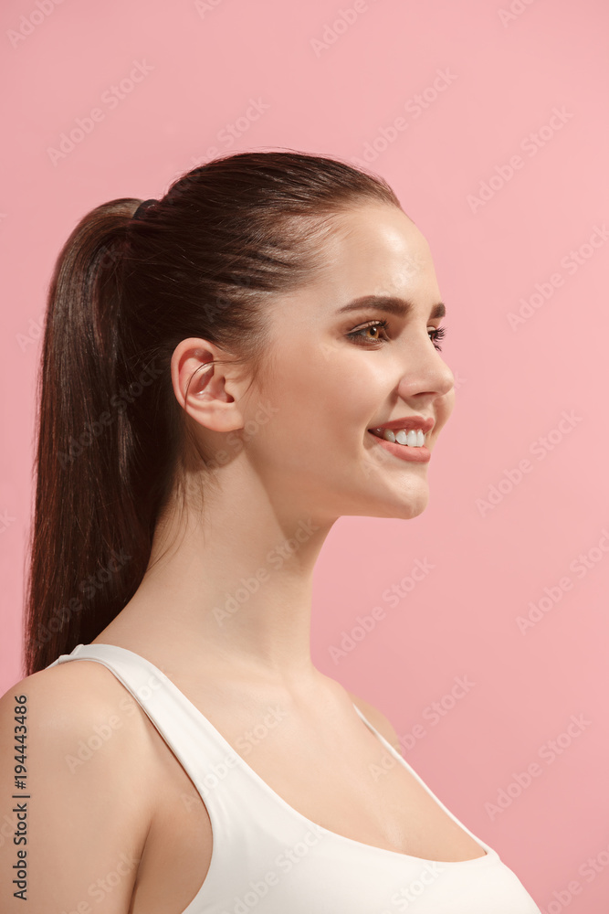 The happy woman standing and smiling against pink background. The happy woman standing and smiling against pink background.