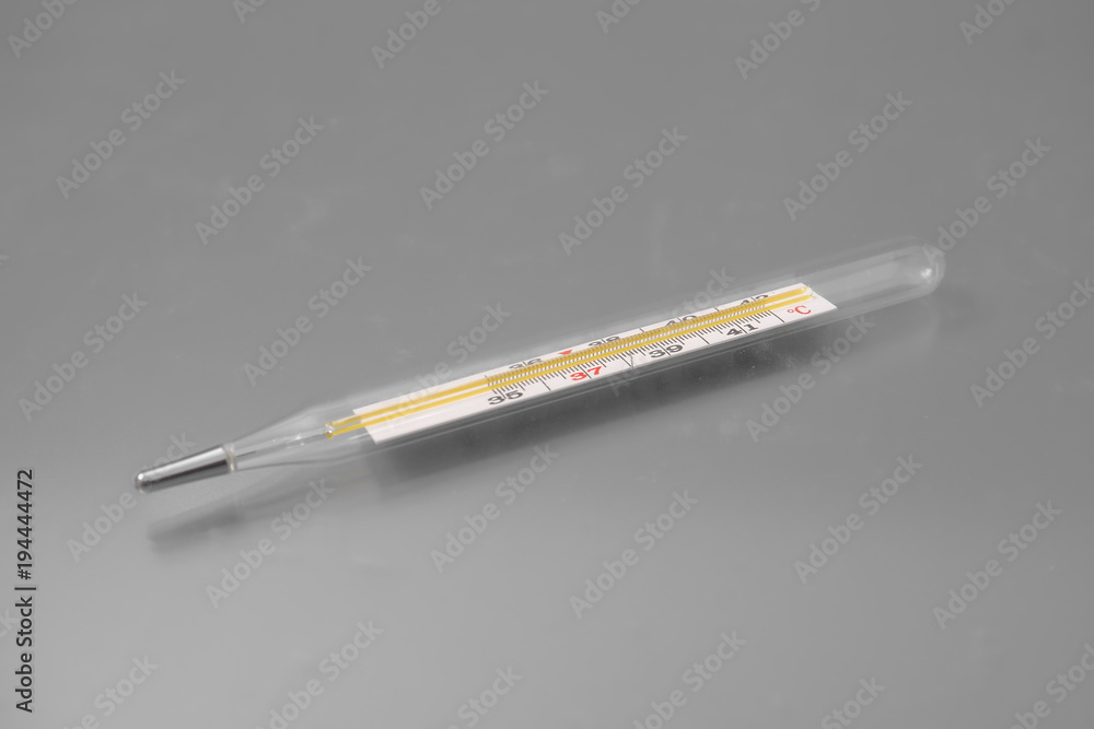 medical thermometer with tablets and a spray for the nose on a gray background in the studio. medical thermometer with tablets and a spray for the nose on a gray background in the studio.