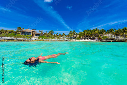 Attractive young woman relaxing in turquoise waters of Caribbean Sea in front of paradise beach in Tulum, close to Cancun, Riviera Maya, Mexico