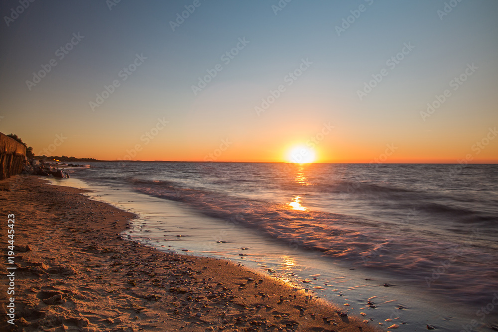 закат в балтийское море с видом на пляж и камни