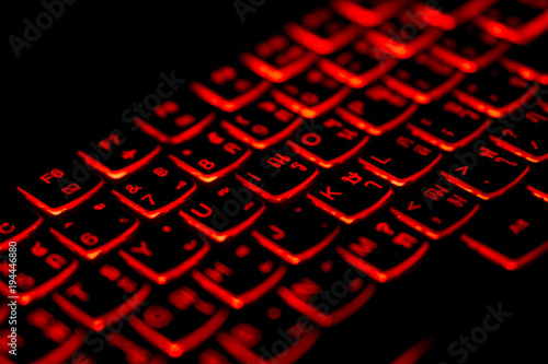 Diagonally Thai - English language laptop keyboard with glowing red light for hacking ,gaming,program developing concept,soft focus