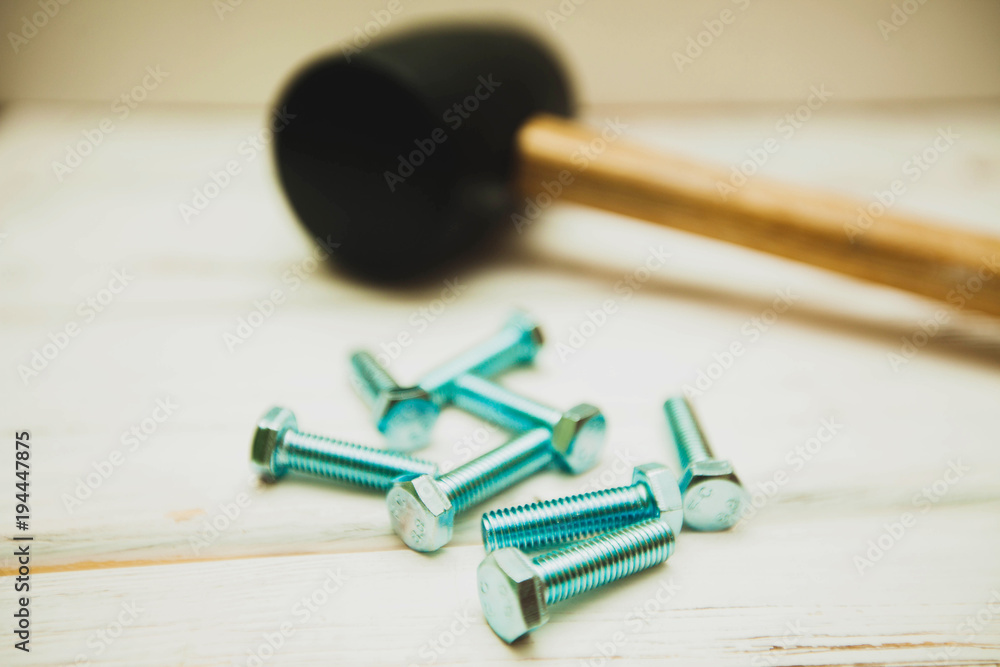 Repair carpenter tools: rubber hummer and screws on white old wooden background, top view, copy space Repair carpenter tools: rubber hummer and screws on white old wooden background, top view, copy space