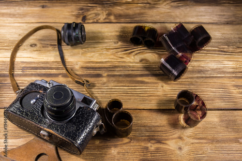 Retro photo camera with photo film and lens on wooden table