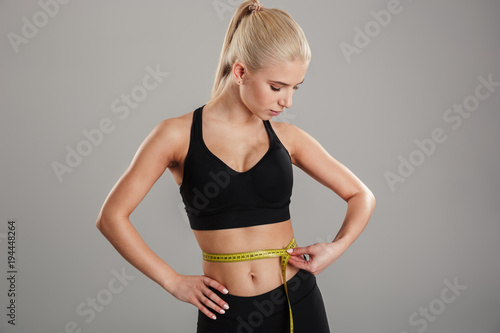 Portrait of a slim young sportsgirl holding measuring tape