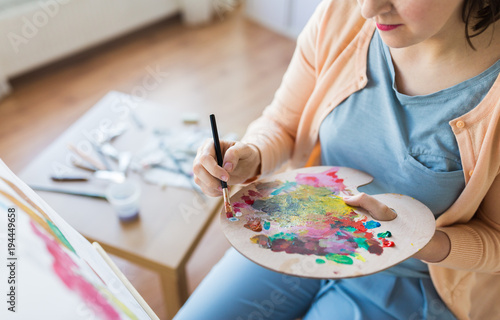 artist with palette and brush painting at studio