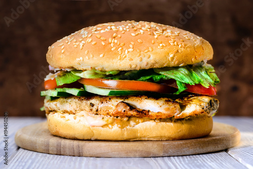 Delicious tasty burger with beef, tomatoes, salad and sauce on board on wooden  background, close-up