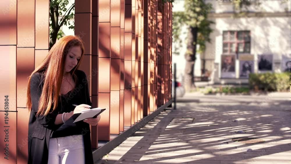 Young student doing notes in the city
