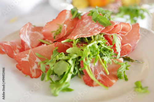 Tyrolean bacon slices and arugula in a dish