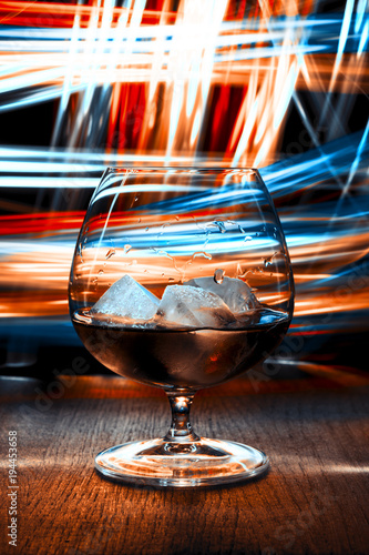 Glass of whiskey on bright background.