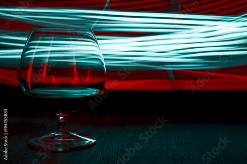 A glass of cognac on bright background light effect.