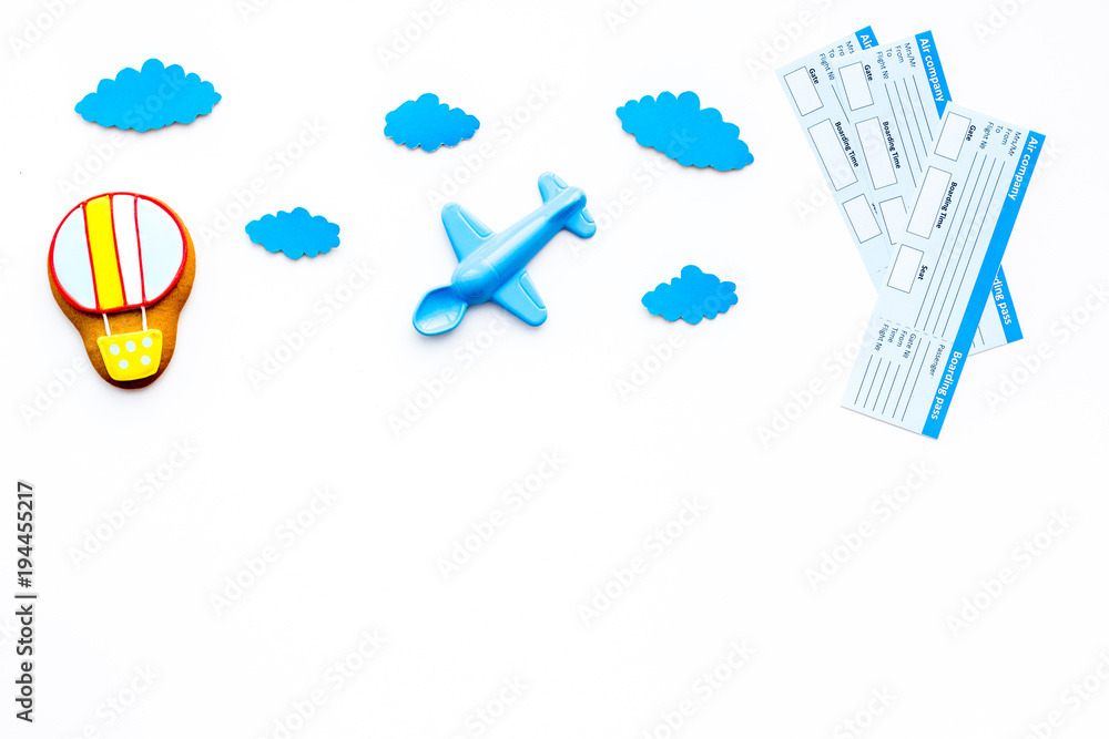 Travelling with child concept. Airplan toy, air balloon cookie, airplan tickets on white background top view copy space Travelling with child concept. Airplan toy, air balloon cookie, airplan tickets on white background top view copy space