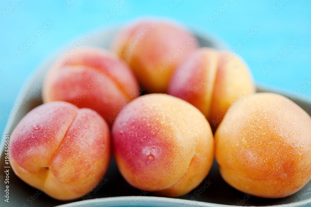Peaches delicious fruit in a heart shaped plate on a blue wooden background Peaches delicious fruit in a heart shaped plate on a blue wooden background