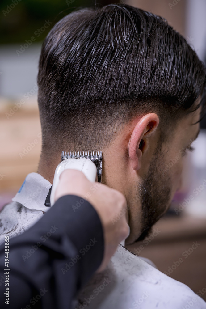 Hairdresser cutting hair to a client with an electric machine Hairdresser cutting hair to a client with an electric machine