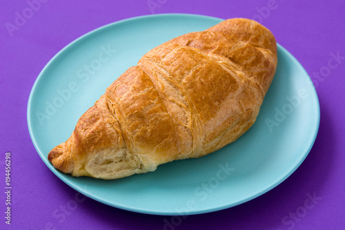 Croissant on violet background. 