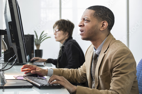 Business man working on computer looking frustrated, upset