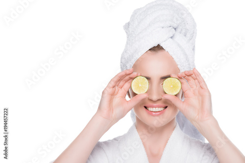 Woman with clean skin closing eyes by slices of lime isolated on white